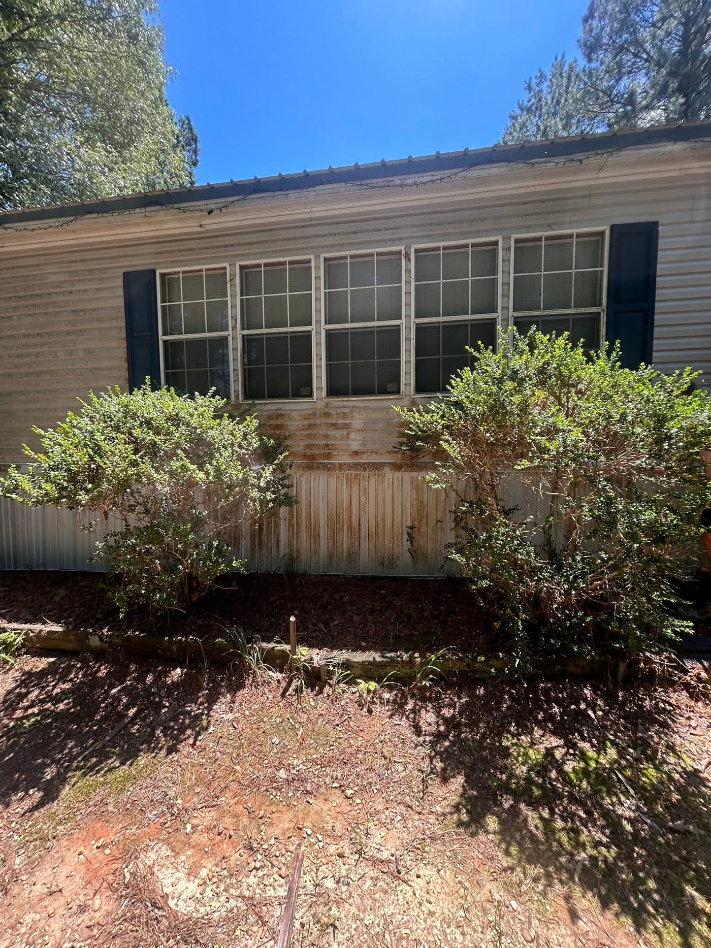 Mobile home front with rust stains and grime on the siding before pressure washing